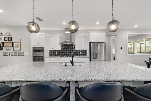 kitchen featuring sink, stainless steel appliances, white cabinets, decorative light fixtures, and wall chimney exhaust hood