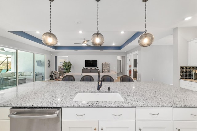 kitchen featuring sink, stainless steel dishwasher, white cabinets, and a tray ceiling