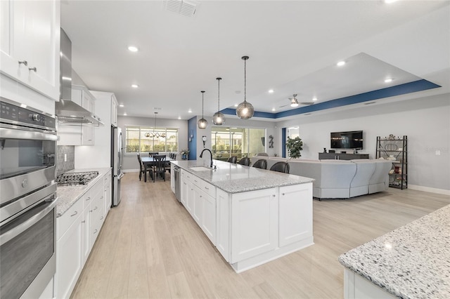 kitchen featuring white cabinetry, a large island, and wall chimney range hood