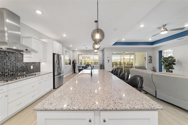 kitchen with a spacious island, stainless steel appliances, and wall chimney exhaust hood