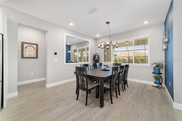 dining area featuring a notable chandelier, a healthy amount of sunlight, and light wood-type flooring