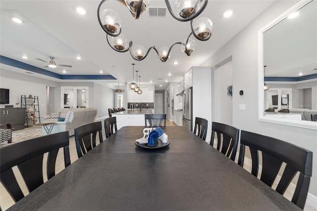 dining area with ceiling fan and a tray ceiling