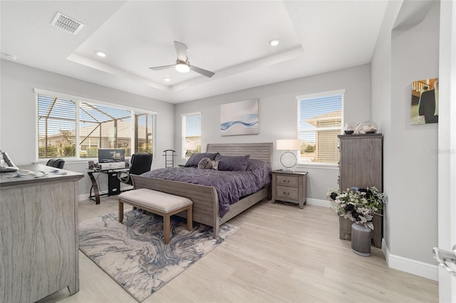 bedroom featuring ceiling fan, a raised ceiling, and light hardwood / wood-style flooring