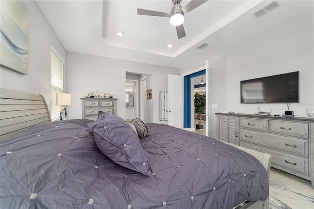 bedroom featuring connected bathroom, light hardwood / wood-style flooring, a raised ceiling, and ceiling fan