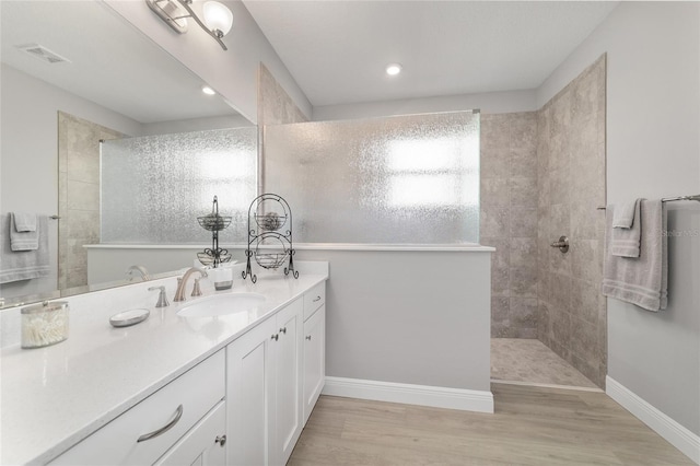 bathroom featuring hardwood / wood-style flooring, vanity, and a tile shower