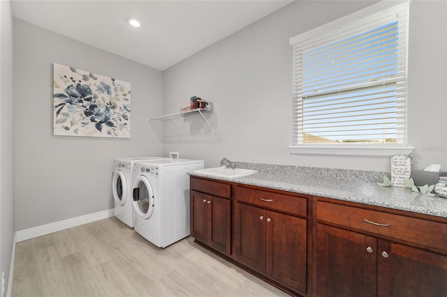 washroom featuring cabinets, sink, washing machine and clothes dryer, and light wood-type flooring