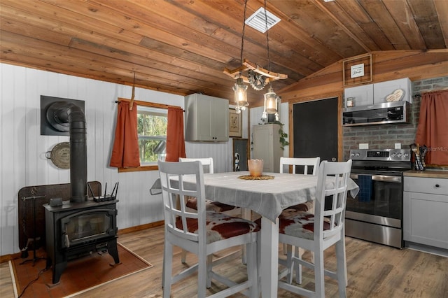 dining area featuring wood ceiling, lofted ceiling, light hardwood / wood-style flooring, and a wood stove