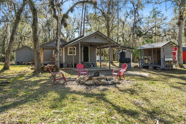 rear view of property with a fire pit, a yard, and a storage shed