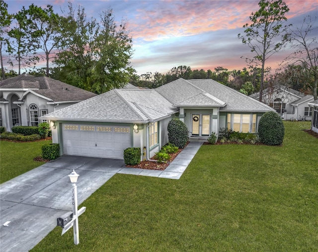 ranch-style house featuring a garage and a lawn