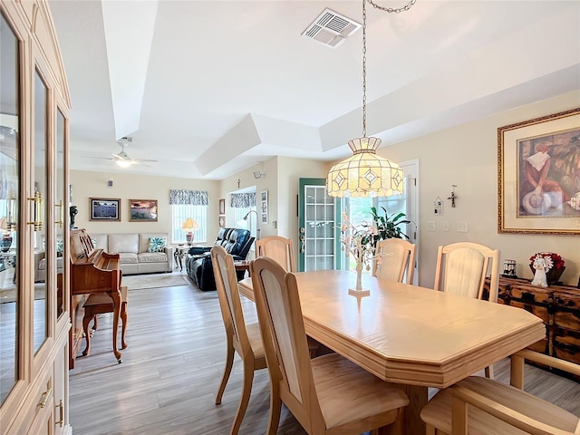 dining space featuring ceiling fan, a raised ceiling, and hardwood / wood-style floors