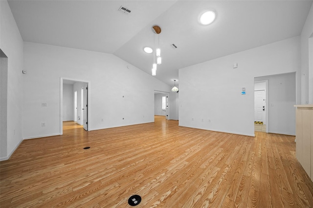 unfurnished living room with visible vents, baseboards, light wood-style floors, and lofted ceiling