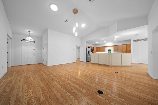 unfurnished living room featuring light wood finished floors, visible vents, baseboards, and lofted ceiling