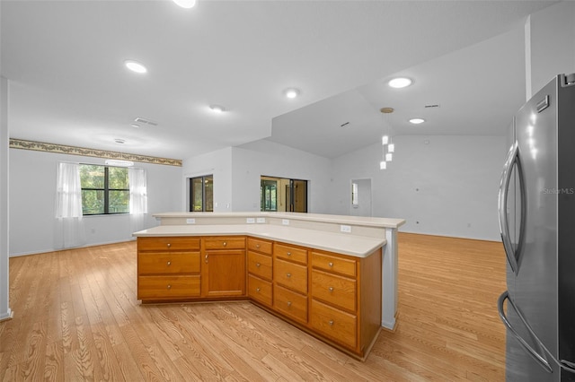 kitchen featuring open floor plan, freestanding refrigerator, light wood finished floors, lofted ceiling, and light countertops