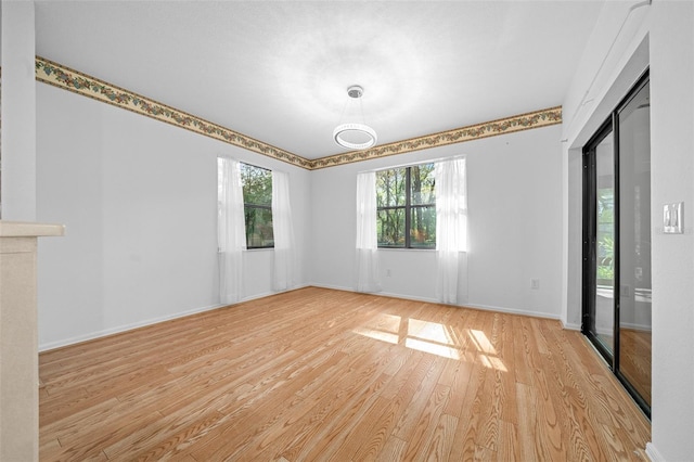 spare room with a glass covered fireplace, light wood-style floors, and baseboards