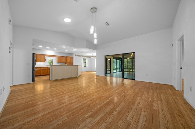 unfurnished living room featuring lofted ceiling, light wood-style floors, and baseboards