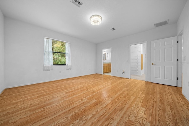 unfurnished bedroom featuring visible vents, connected bathroom, and light wood finished floors