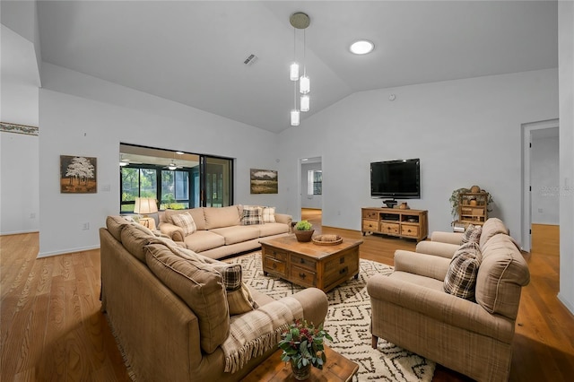 living area featuring lofted ceiling, baseboards, visible vents, and light wood finished floors