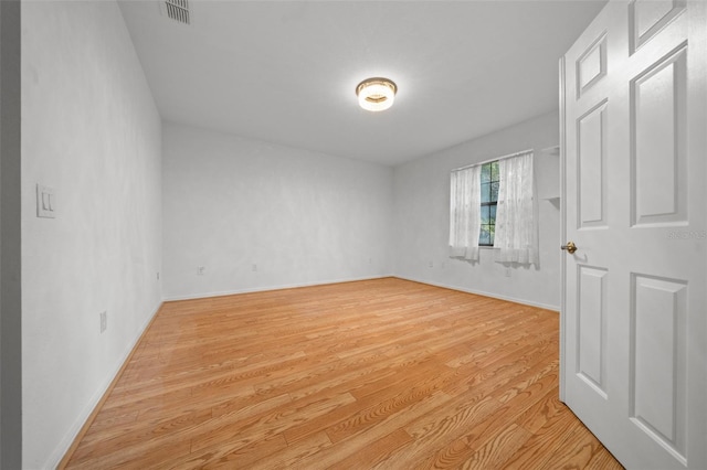 unfurnished room featuring visible vents, light wood-style flooring, and baseboards