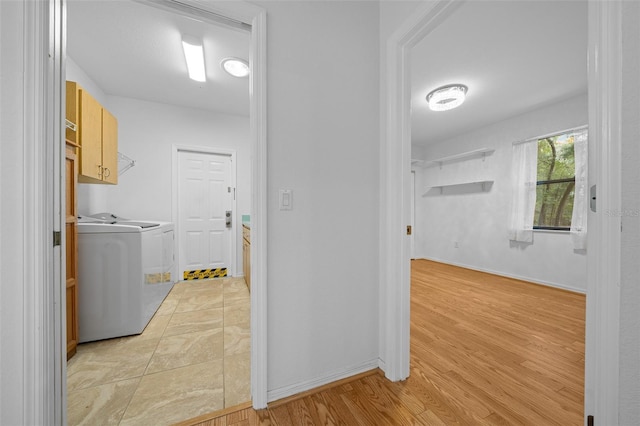 clothes washing area featuring washer and clothes dryer, cabinet space, light wood finished floors, and baseboards