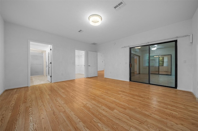 unfurnished bedroom featuring visible vents, ensuite bathroom, access to outside, light wood-style floors, and baseboards