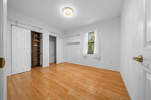 unfurnished bedroom featuring light wood-style flooring, two closets, and baseboards