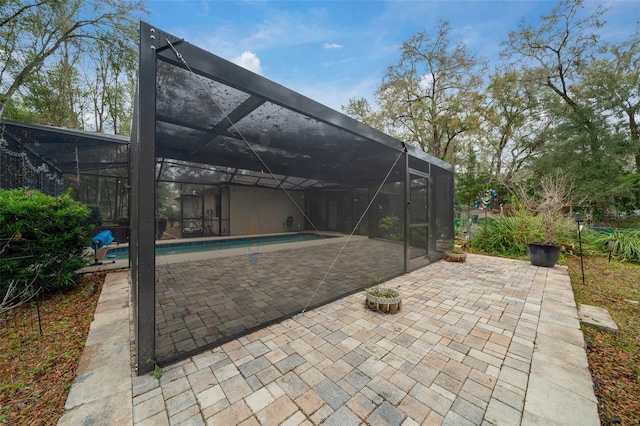 outdoor pool featuring glass enclosure and a patio