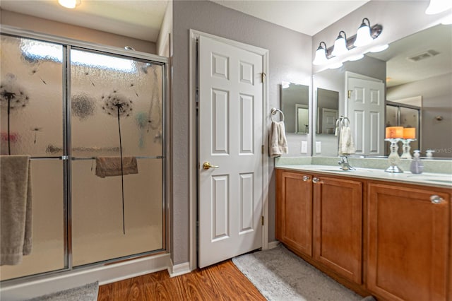 bathroom with vanity, an enclosed shower, and wood-type flooring