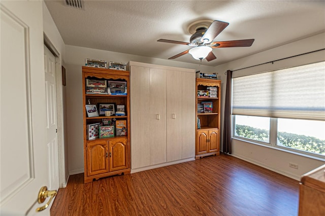 unfurnished bedroom featuring a textured ceiling, dark wood-type flooring, and ceiling fan