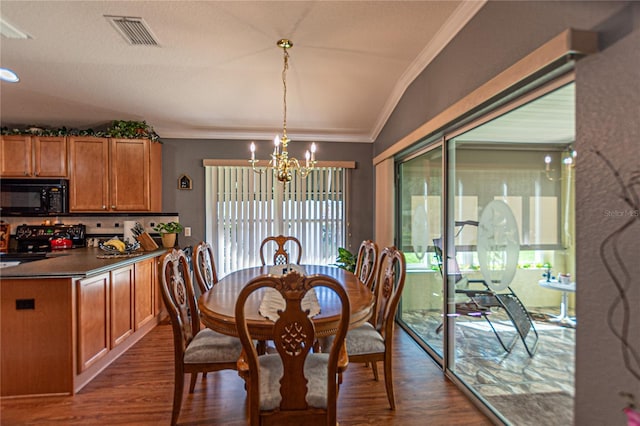 dining space with dark hardwood / wood-style flooring, ornamental molding, a chandelier, and lofted ceiling