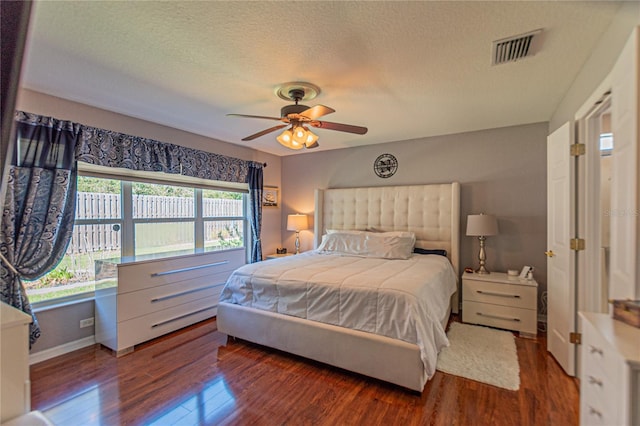 bedroom featuring ceiling fan, dark hardwood / wood-style floors, and a textured ceiling