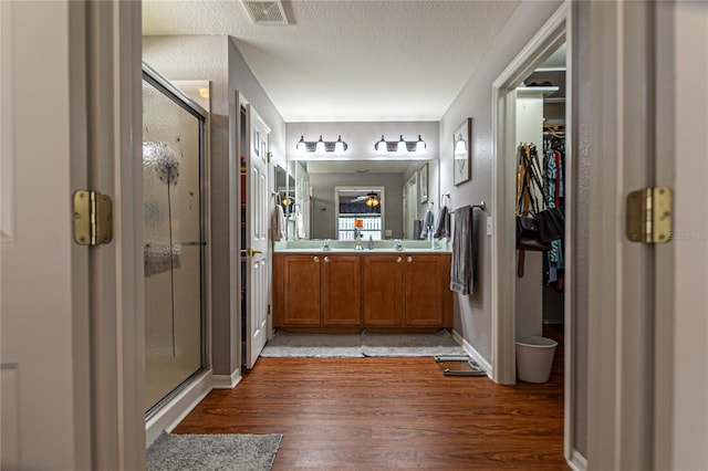 bathroom featuring vanity, a shower with door, a textured ceiling, and hardwood / wood-style floors