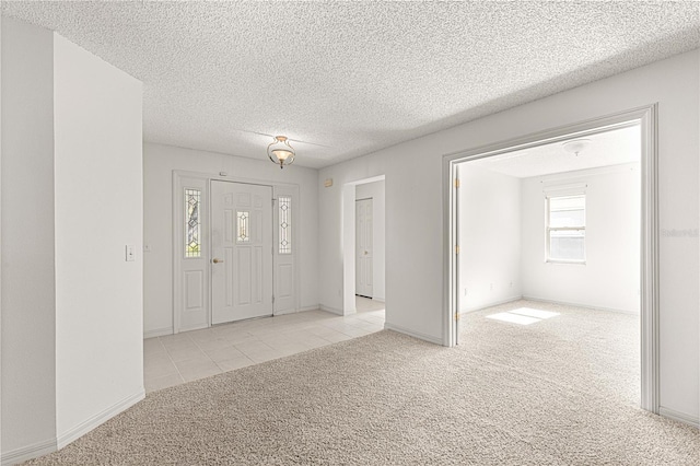 tiled entrance foyer featuring a textured ceiling, baseboards, and carpet floors