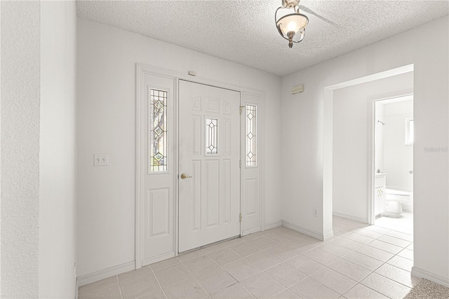 entrance foyer with light tile patterned floors, baseboards, and a textured ceiling