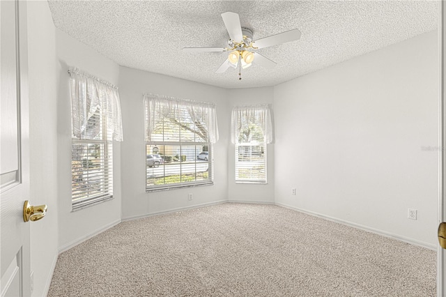 carpeted empty room with ceiling fan, baseboards, and a textured ceiling