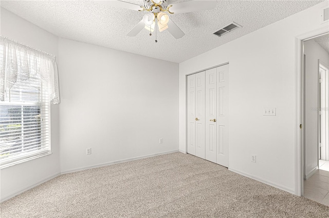 unfurnished bedroom featuring a closet, visible vents, a textured ceiling, and carpet floors