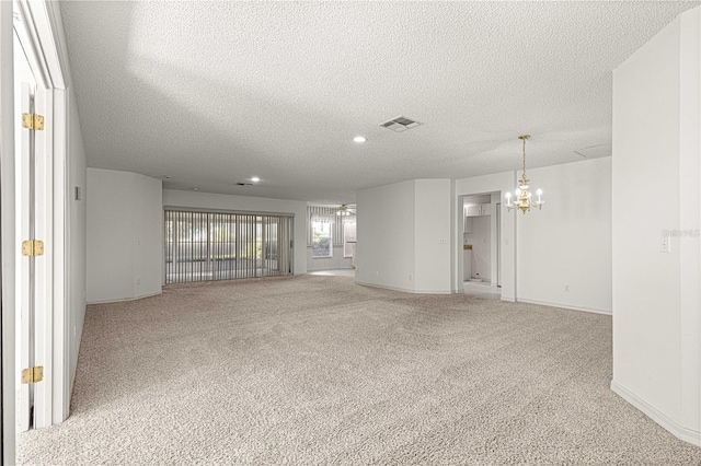 carpeted empty room featuring visible vents, a textured ceiling, recessed lighting, baseboards, and a chandelier