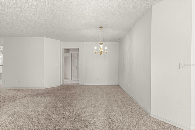 spare room featuring baseboards, carpet flooring, a textured ceiling, and an inviting chandelier