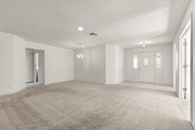 interior space featuring a textured ceiling, light colored carpet, visible vents, and a chandelier