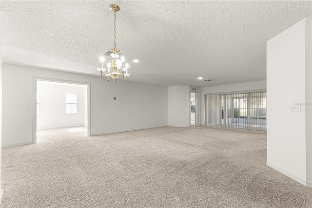 spare room featuring a notable chandelier, baseboards, carpet, and a textured ceiling