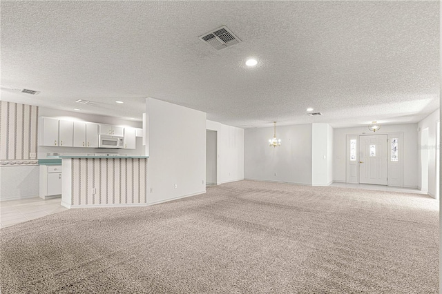 unfurnished living room with visible vents, light colored carpet, and a textured ceiling