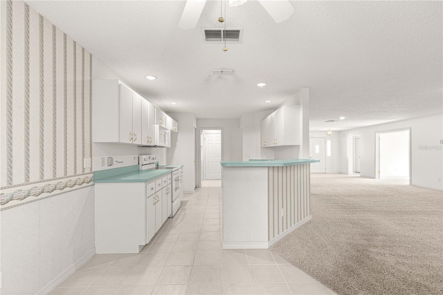 kitchen featuring visible vents, light carpet, electric range, white cabinetry, and a ceiling fan