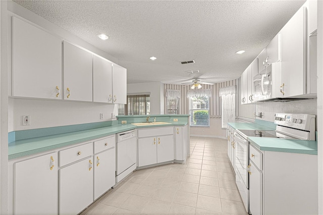 kitchen with white appliances, a ceiling fan, a sink, light countertops, and white cabinetry