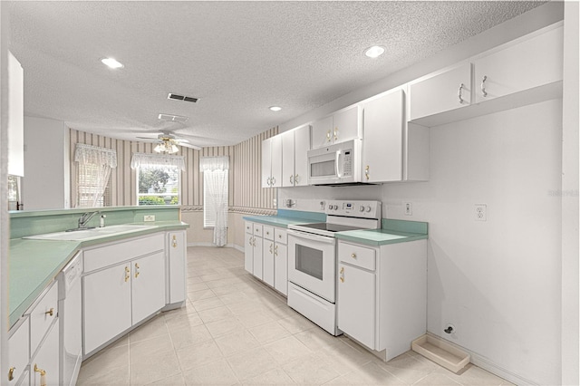 kitchen with white appliances, a textured ceiling, ceiling fan, and white cabinetry