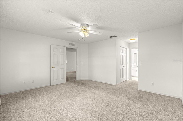 unfurnished room with a textured ceiling, light colored carpet, visible vents, and ceiling fan