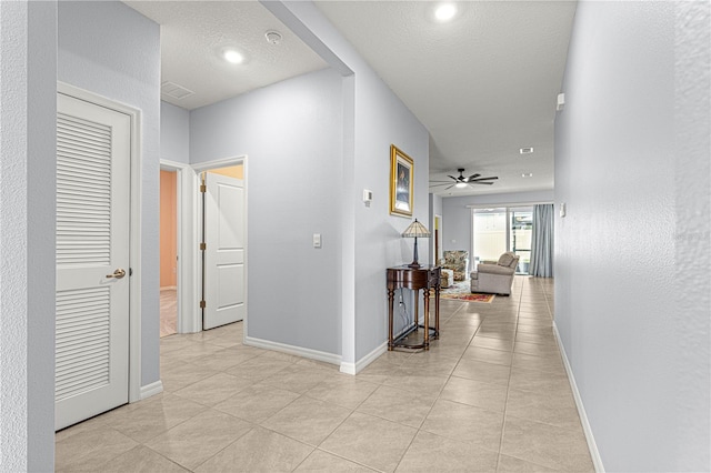 corridor featuring a textured ceiling and light tile patterned flooring