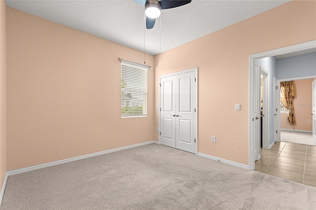 unfurnished bedroom with a textured ceiling, ceiling fan, light colored carpet, and a closet