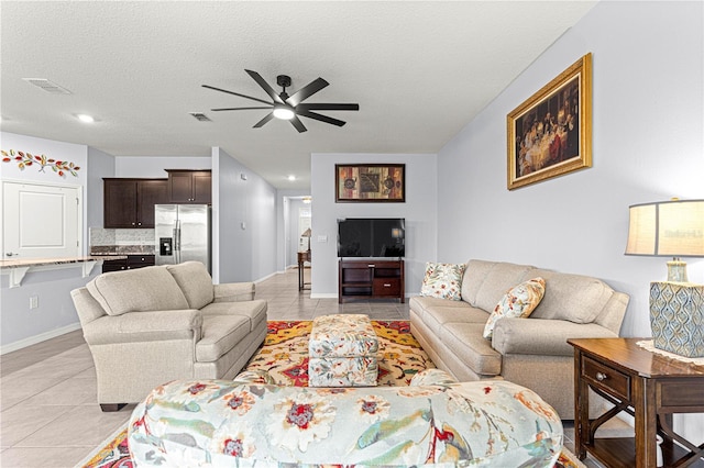 living room featuring a textured ceiling, ceiling fan, and light tile patterned flooring