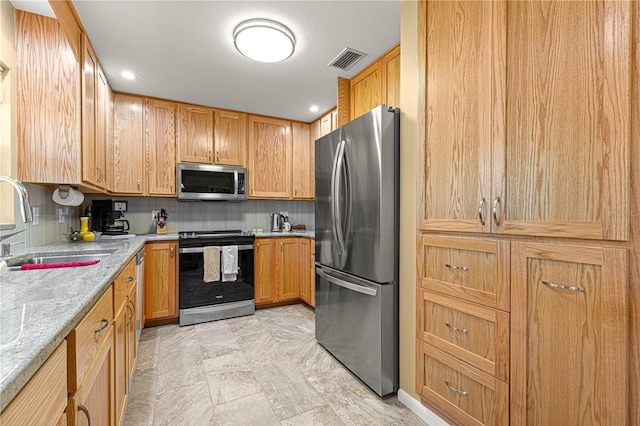 kitchen featuring appliances with stainless steel finishes, sink, light stone counters, and tasteful backsplash