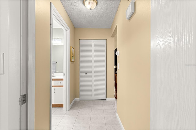 hallway featuring light tile patterned flooring and a textured ceiling