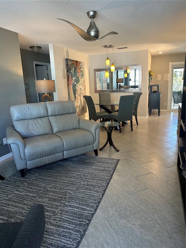 living room with ceiling fan and a textured ceiling